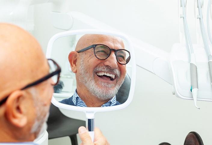 A man looking at his smile in a mirror