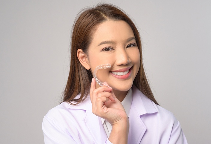 Smiling patient holding clear aligner