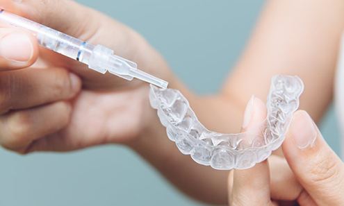 Person applies whitening agent to dental trays